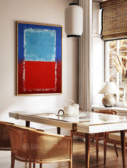 Abstract art print with a light blue rectangle over a red rectangle, bordered by darker blue and, in a styled room mockup