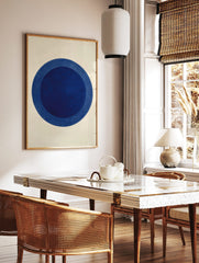 Minimalist abstract art print with two concentric blue circles on a white background, in a styled room mockup
