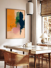 Abstract art print with orange, navy blue, green, and pink brushstrokes on a light background, in a styled room mockup
