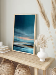 Abstract coastal landscape painting with dark blue sky, pink horizon, and textured blue, in an alternate framed mockup