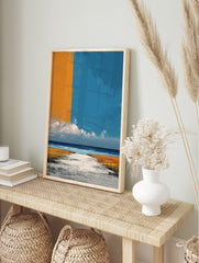 Abstract coastal landscape art print with orange and blue sky over a textured beach and ocean, in an alternate framed mockup