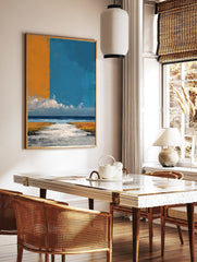 Abstract coastal landscape art print with orange and blue sky over a textured beach and ocean, in a styled room mockup