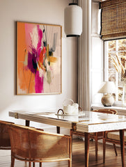 Abstract painting with orange, hot pink, gold, and dark brushstrokes, white lines, and splatters, in a styled room mockup