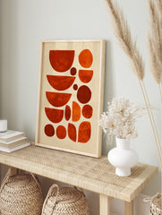Abstract geometric art print with organic shapes in varying shades of orange and red against, in an alternate framed mockup