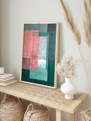 Abstract geometric wall art with layered pink, grey, and teal rectangles, creating a sense of, in an alternate framed mockup