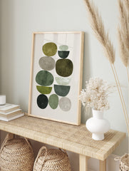 Abstract art print with stacked organic and semi-circular shapes in green and grey earth tones, in an alternate framed mockup