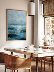 Abstract ocean seascape wall art print with blue textured waves, green accents, and bright horizon, in a styled room mockup