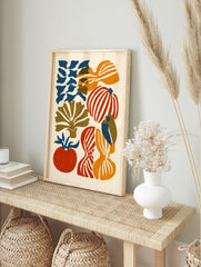 Abstract illustrative wall art with organic red, orange, and blue vegetable shapes on a cream, in an alternate framed mockup