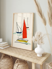 Minimalist abstract sailboat wall art with red, blue, and yellow sails and black line work on, in an alternate framed mockup
