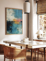 Abstract seascape art print with textured blues, oranges, and white, depicting a sunset over water, in a styled room mockup