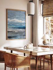 Textured abstract seascape painting with blue ocean, grey sky, and sandy beach in painterly style, in a styled room mockup