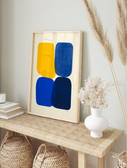 Abstract art print with four rounded shapes in yellow, blue, and navy on an off-white, in an alternate framed mockup