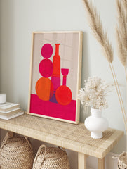 Abstract still life art print with pink and orange geometric bottle and sphere shapes on a, in an alternate framed mockup