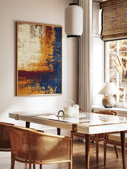 Abstract art print with distressed textures in cream, golden-yellow, deep blue, and burgundy, in a styled room mockup