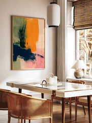 Abstract art print with bold orange, navy, and green brushstrokes on a pale pink background, in a styled room mockup