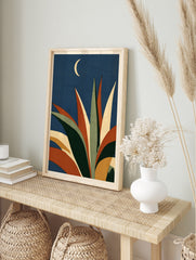 Abstract agave plant illustration with orange and green leaves against a dark blue sky with a, in an alternate framed mockup