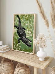 Linocut style alligator swimming through a green swamp, viewed from above, with roots and, in an alternate framed mockup