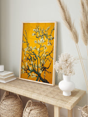 Close-up of white almond blossoms on dark branches against a vibrant yellow background, in an alternate framed mockup