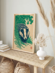 Illustrative green and beige badger animal art print emerging from foliage in a woodcut style, in an alternate framed mockup