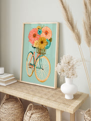 Illustrative bicycle with an orange frame and basket full of colourful flowers on a soft teal, in an alternate framed mockup