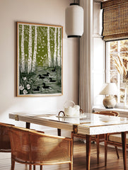 Green linocut art print of white birch trees, flying birds, and black ducks in a pond with reeds, in a styled room mockup
