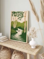Illustrative wall art of birch trees with green leaves, a winding stream, reeds, and three, in an alternate framed mockup