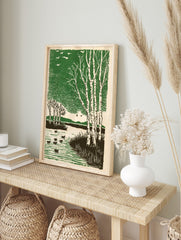 Woodcut style print of white birch trees, ducks on a pond, and flying birds against a green, in an alternate framed mockup