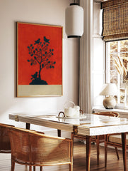 Black silhouette of a tree with three birds on a vibrant reddish-orange background, with a beige, in a styled room mockup
