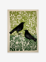 Linocut style print of two black birds amidst green and white flowers and foliage