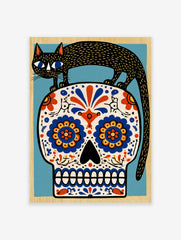 Black cat standing on a decorative sugar skull with vibrant blue and orange floral patterns, illustrative art print