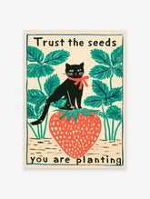 Black cat with red bow on a large strawberry, green leaves, cream background, text 'Trust the seeds you are planting'