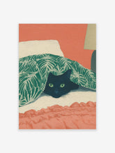 Illustrative print of a black cat with green eyes peeking from under a green tropical leaf blanket