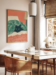 Illustrative print of a black cat with green eyes peeking from under a green tropical leaf blanket, in a styled room mockup