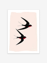 Black Swallows Wall Art print showing two minimalist black swallows with red details flying against a light pink background.
