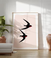 Black Swallows Wall Art print showing two minimalist black swallows with red details flying against a light pink background. - Image 3