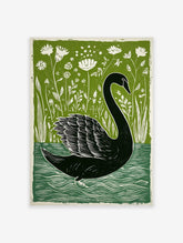 Black swan linocut print on water with green botanical foliage and white flowers in background