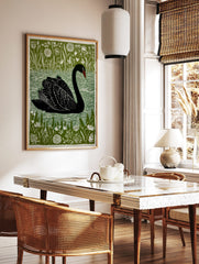 Black swan linocut style art print on green background with white botanical plants and water, in a styled room mockup