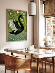 Black swan with white wings in a bold illustrative style, surrounded by green foliage and white, in a styled room mockup