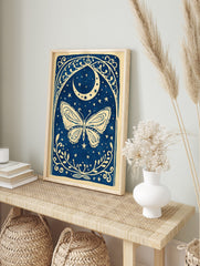 Illustrative blue and white butterfly with crescent moon, stars, and ornate botanical border, in an alternate framed mockup