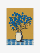 Blue flower wall art featuring a botanical illustration of vibrant blue flowers in a white vase on a checkered table against a gold background.