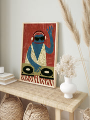 A blue frog DJ wearing headphones and sunglasses behind turntables, graphic illustrative wall, in an alternate framed mockup