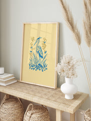 Illustrative blue heron standing amongst blue cattails and reeds with golden flourishes on a, in an alternate framed mockup
