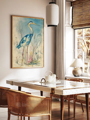 Blue heron bird wall art illustration in watercolour style, standing amidst reeds with a light blue, in a styled room mockup
