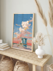 Blue lifeguard hut on a sandy beach with thick impasto clouds in a pink and blue sky, in an alternate framed mockup