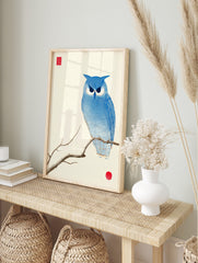 Blue owl illustration on a branch with concentric lines, red seal, and red circle on, in an alternate framed mockup