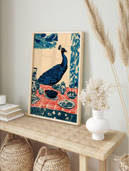 Illustrative blue peacock seated at a dining table with red patterned tablecloth and ceramic, in an alternate framed mockup