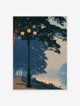 Blue river evening poster with vintage lamp post, lit lanterns, silhouetted trees and peach sunset reflections on water