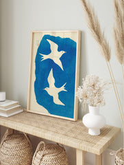 Two white illustrative birds flying against a textured blue background with Japanese text and, in an alternate framed mockup
