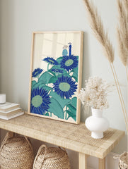 Illustrative blue sunflowers with green leaves and two figures in hats on a cream background, in an alternate framed mockup