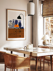 Still life art print featuring four patterned blue and white vases, a bowl of oranges, and a desk, in a styled room mockup